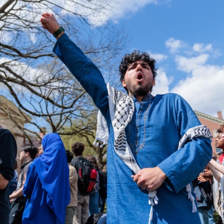 Studierende bei einer Solidaritätskundgebung an der Brown University in Rhode Island am 24.04.2024 mit Palästinensertuch und erhobener Faust.
