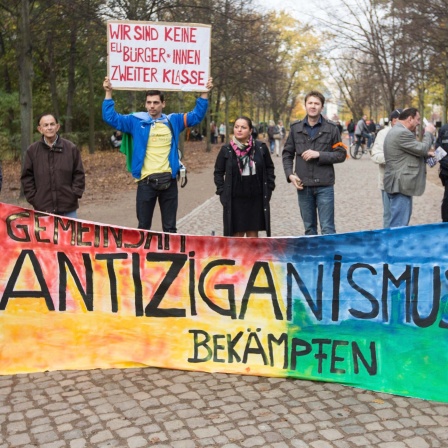 "Gemeinsam Antiziganismus bekämpfen" steht vor dem Mahnmal für Sinti und Roma in Berlin bei einer Kundgebung auf einem Banner.