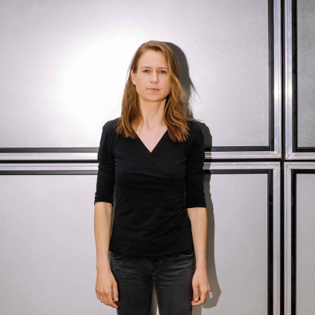 Medienpsychologin Maren Urner steht vor einer Wand aus Stahlelementen.