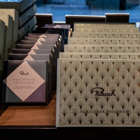 Pralinen- und Schokoladenpackungen stehen in einem Regal in der Berliner Schokoladen-Manufaktur Rausch am Gendarmenmarkt.