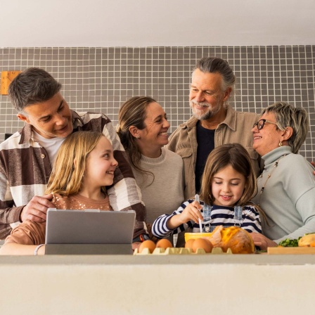 Drei-Generationen-Familie genießt gemeinsame Zeit in der Küche. 