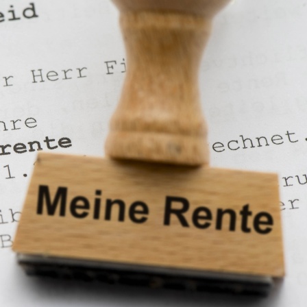 Ein Holzsstempel auf dem "Meine Rente" steht liegt auf einem Rentenbescheid. Symbolbild