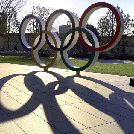 Eine aufgestellte Skulptur der Olympischen Ringe in einer Strasse von Tokio wirft lange Schatten