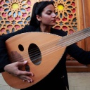 Eine junge iranische Musikerin mit dunklen Haaren, hält eine Oud in der Hand und stimmt sie.
