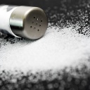 Salz liegt ausgeschüttet vor einem Salzstreuer.