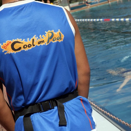 Symbolbild: Ein Mitglied des Konfliktlotsen-Projekts «Bleib cool am Pool» beobachtet vom Beckenrand im Sommerbad Pankow das Badegeschehen