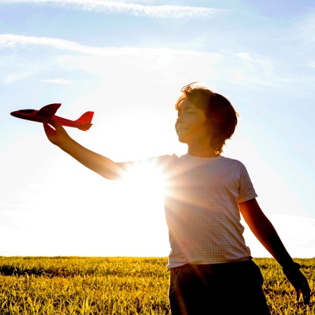 Junge spielt in der Sonne mit einem Spielzeugflugzeug