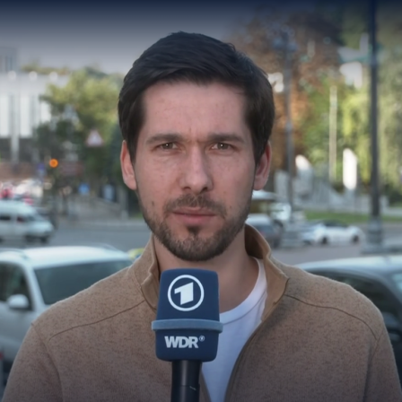 Vassili Golod steht mit einem Mikrofon in der Innenstadt von Kiew