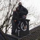 Demonstrierende sitzen während der Räumung des Dorfes Lützerath auf einem Hausdach