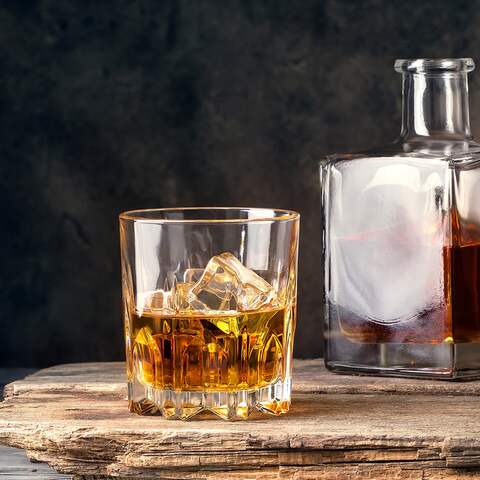 Ein Glas mit Whiskey neben einem Holzfass