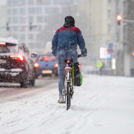 Ein Radfahrer fährt bei dichtem Schneefall durch die Innenstadt. Schnee und Eis haben Straßen und Gehwege in weiten Teilen Deutschlands in gefährliche Rutschbahnen verwandelt. 17.01.2024.