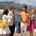 Im Still aus der zweites Staffel von "The White Lotus" stehen zwei weiße, gut gekleidete Paare auf einem Bootsanleger in Italien und stoßen mit Sektgläsern an.