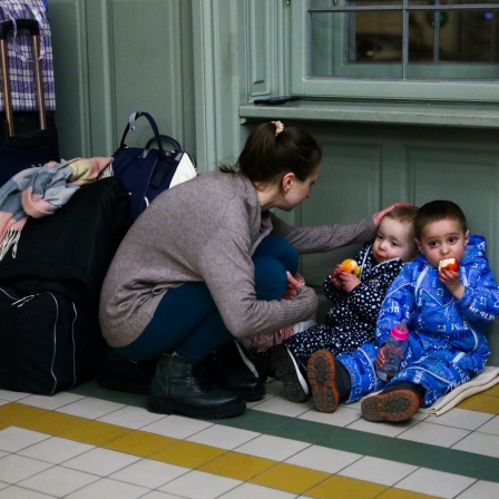 Eine Mutter mit Kindern ruht sich in einem provisorischen Unterstand in einem Bahnhofsgebäude aus, nachdem sie mit dem Zug nach Polen gekommen ist.