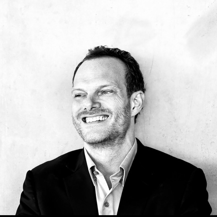 Hell belichtetes Schwarz-weiß-Porträt von Lars Vogt; Mann lachend mit Blick leicht zur Seite