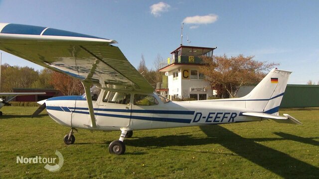 Ein kleines Flugzeug, im Hintergrund der Tower auf dem Flugplatz der Fliegerfreunde Conneforde.