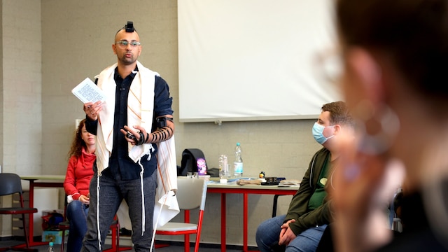 Ein Mann in traditionell jüdischer Kleidung steht vor einer Schulklasse