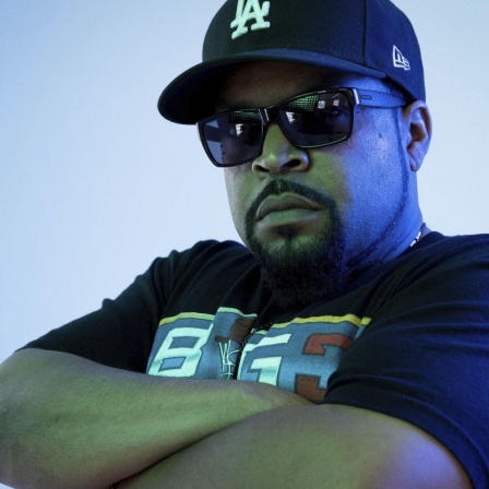 Der Rapper Ice Cube mit Cappy, Sonnenbrille und verschränkten Armen.