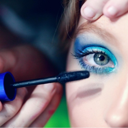 Ein Kind schminkt sich mit blauer Wimperntusche.