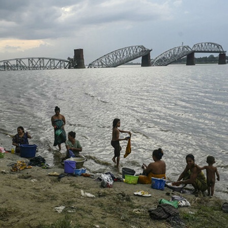 Menschen baden im Irrawaddy-Fluss vor der eingestürzten Ava-Brücke in Mandalay (13. April 2025)
