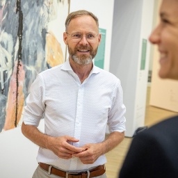 Museumsdirektor Andreas Beitin im weißen Hemd, spricht mit zwei OPersonen, die vor ihm stehen.