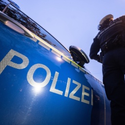 Eine Polizistin steht im Rahmen eines Fototermins neben einem Polizeifahrzeug