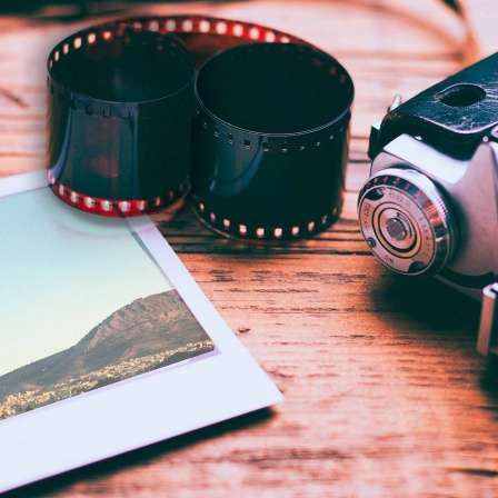 Tisch mit Kamera, Filmrolle und einem Polaroidfoto.