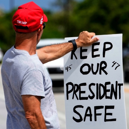 ein Trumpanhänger hält ein Schild in der Hand, auf dem steht: " keep our president safe "