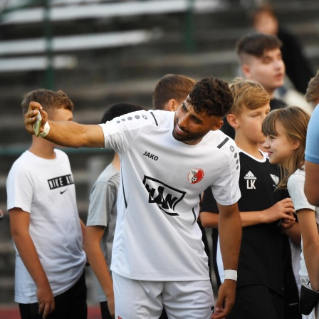  Der Fussballer Nader El-Jindaoui umringt von Fans, die ein Selfie mit ihm wollen, Berlin 2022.