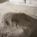 Eine Katze schläft unter einer Bettdecke, nur die Wölbung des Stoffes ist sichtbar.