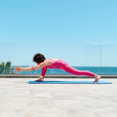 So kann Wohlbefinden aussehen: Eine Frau macht eine Yogaübung auf der Terrasse eines Hotels.