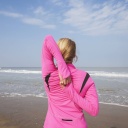 Eine Frau in Sportkleidung dehnt sich an einem Strand (Symbolbild)