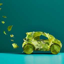 Ein Auto aus grünen Blättern mit einer Spur aus Blättern aus dem Auspuff.