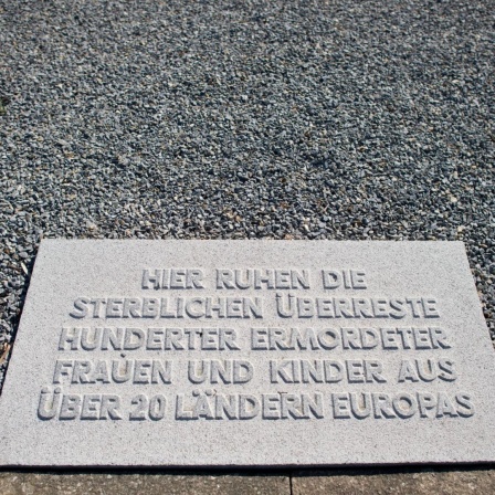 Eine Gedenkplatte in der Gedenkstätte des KZ Ravensbrück in Fürstenberg/Havel (Brandenburg), umgeben von schwarzem Schotter.