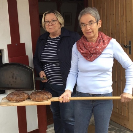 Die Hobby-Bäckerinnen Maria Schwarze-Kaufmann (rechts) und Sigrid Schindler holen die Brote aus dem Elektro-Ofen im Backhaus Bobenheim am Berg (Pfalz)