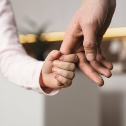 Kind hält Hand eines Erwachsenen