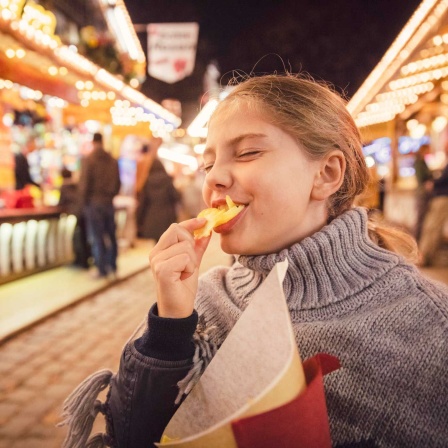 ARCHIV, München, 17.03.2020: Mädchen isst Chips auf einem Rummel (Bild: picture alliance / Westend61)