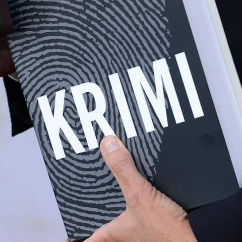 Ein Mann hält ein Buch mit dem Schriftzug &#034;Krimi&#034;