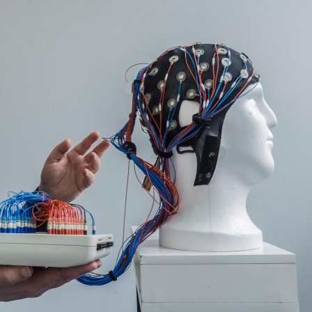 Eine weiße Büste trägt eine Kappe mit angeschlossenen Drähten zur nichtinvasiven Hirnstimulation.