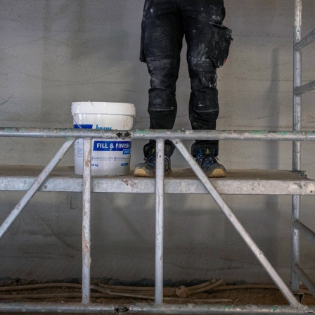 Ein Handwerker auf einem Baugeruest auf einer Baustelle in Berlin 