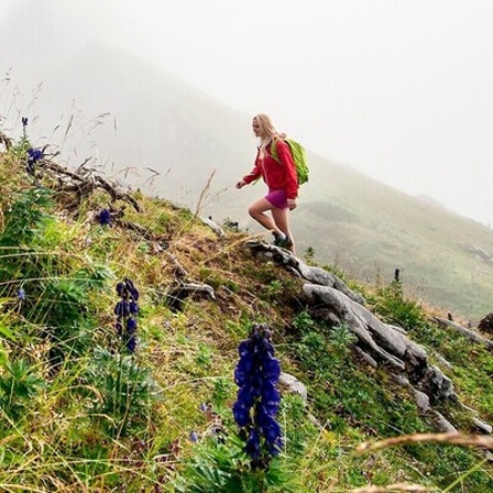 Eine Frau steigt einen Berg hoch. Sie geht Wandern.