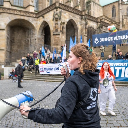 Die "Junge Alternative" posiert auf den Domstufen für ein Gruppenfoto während der Demonstration der AfD unter dem Motto: "Der Osten steht zusammen", eine junge Frau ruft in ein Megafon, Erfurt 2023.