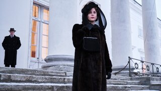 Szenenbild aus der norwegischen Serie "Atlantic Crossing": Eine trauernde Frau in schwarz vor einem großen weißen Gebäude.