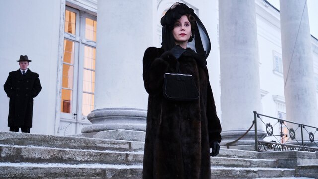 Szenenbild aus der norwegischen Serie "Atlantic Crossing": Eine trauernde Frau in schwarz vor einem großen weißen Gebäude.