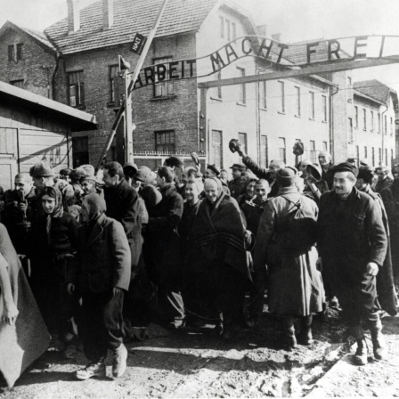 Überlebende von Auschwitz verlassen das Lager. Das Foto wurde von einem sowjetischen Fotografen während der Herstellung eines Films über die Befreiung des Lagers gemacht. 