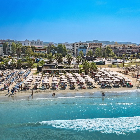 Der Strand von Golem, Durres, mit Sonnenschirmen und Touristen.