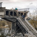 Zwei Ukrainer auf der Flucht klettern eine Leiter auf einer zerstörten Brücke hoch, Kukhari am 19.04.2022.