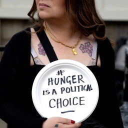 Eine Frau hält bei einer Demonstration ein Schild hoch mit der Aufschrift: "Hunger is a political Choice".