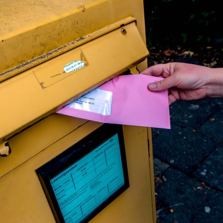 Symbolbild: Ein Briefwahlumschlag wird in einen Briefkasten geworfen.