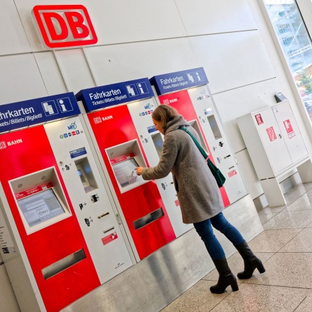 Bahnticketkauf. Die Frau kauft sich die Fahrkarte am Automaten