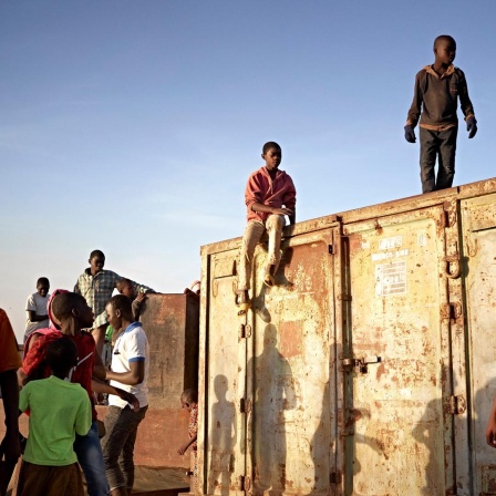 Junge Menschen aus Mali stehen auf einem Container am Niger in Segou.
